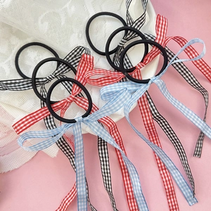 Detail view of ballet-style gingham ribbon hair ties in red, blue, and black colors