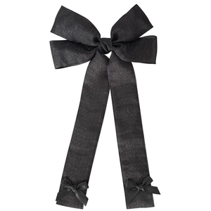 Détail d'un nœud papillon en tulle noir avec de longs rubans et un tissu texturé