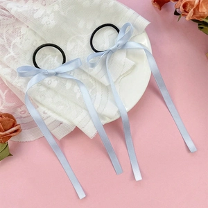 Detail of light blue satin ribbon bow hair ties with long streamers on a flat lay set