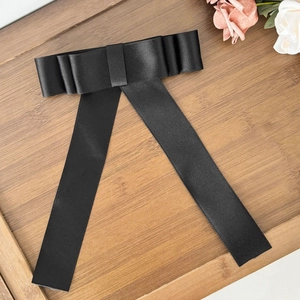 Détail du nœud élégant en satin noir avec de longs rubans sur un plateau en bois