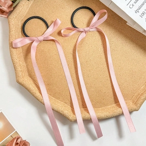 Detail of two pink silk bow hair ties with long ribbons on a decorative tray