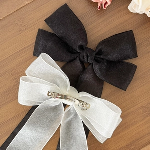 Barrette à cheveux élégante avec nœud en maille noire et crème sur fond en bois chaud