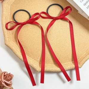 Close-up of two red ballet style satin ribbon hair bows on a vintage decorative tray