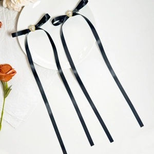 Détail de barrettes en satin noir avec perles en forme de cœur sur une assiette blanche