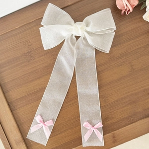 Pince à cheveux élégante avec grand nœud en mesh blanc et rubans roses sur bois