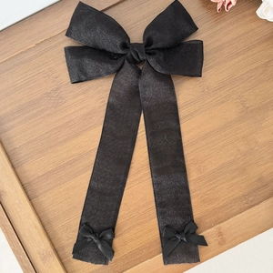 Barrette à nœud papillon en tulle noir avec longs rubans sur plateau en bois