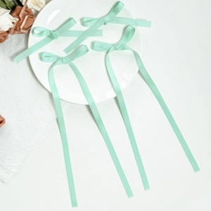 Detail view of mint green grosgrain ribbon hair bows with long streamers on a ceramic plate