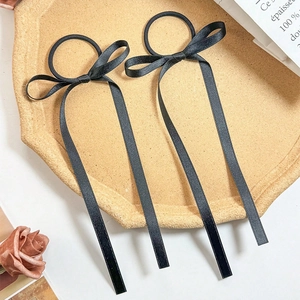 Detail of elegant black satin ribbon bow hair ties with long streamers on a tray