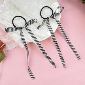 Detail view of two black and white plaid bow hair ties on a delicate lace background
