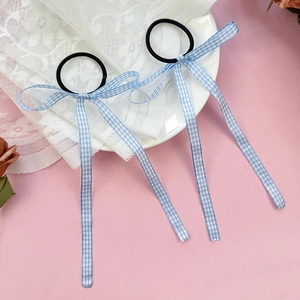 Close-up of blue gingham bow hair ties with long ribbons on soft aesthetic background