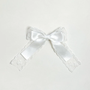 Détail de la pince à nœud double couche en dentelle et ruban de satin blanc élégant