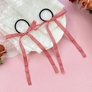 Detail of red and white checkered ribbon bow hair ties with elastic bands on a lace surface