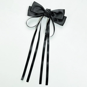 Detail view of large black bow hair clip with 3D rose accent and long flowing ribbons