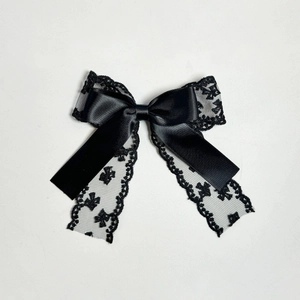 Détail de la pince à cheveux avec nœud en dentelle et satin noir et broderies délicates