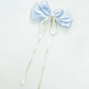 Détail d'une barrette nœud en satin bleu et crème avec de longs rubans fluides