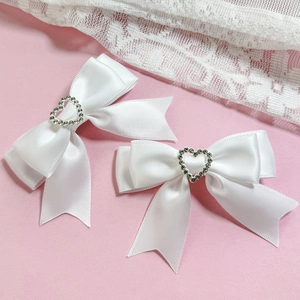 Détails de deux nœuds à cheveux en satin blanc avec cœurs en strass brillants