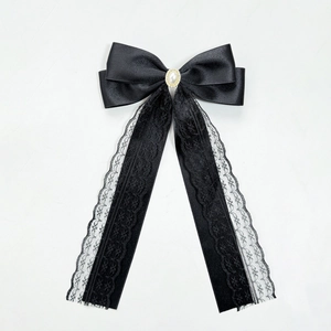 Detail of black satin bow hair clip with lace ribbons and center pearl ornament