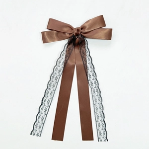 Détail de la pince à cheveux en satin marron avec dentelle noire élégante et longs rubans