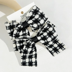 Classic black and white houndstooth bow hair clips on a white display card