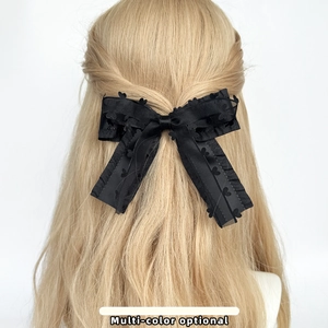 Close-up of black lace bow hair clip with heart embroidery on blonde curly hair