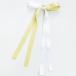 Detail of yellow and white satin ribbon bow hair clip with long flowing streamers