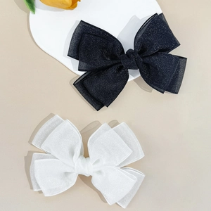 Detail of black and white double-layered mesh bow clips with subtle glitter finish