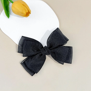 Detail of a large black mesh bow hair clip with silver glitter and layered design