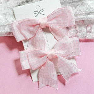 Detalle de dos pinzas para el pelo con lazos de organza rosa y diseño translúcido