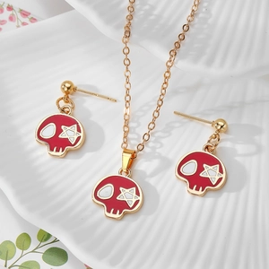 Dettaglio di un set di gioielli teschio mummia rosso con collana e orecchini su porcellana