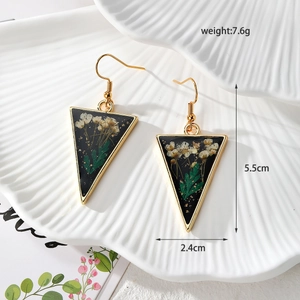 Detail of triangle resin earrings with white dried flowers and gold stainless steel hooks