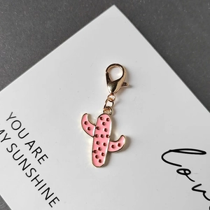 Pink enamel cactus keychain with golden lobster clasp on a white decorative card