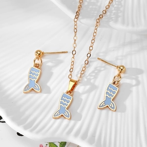 Detailed view of light blue fishtail jewelry set with necklace and earrings on a shell tray