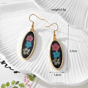 Detail showing oval resin daisy earrings with dried flowers and gold hooks, size 5.5cm