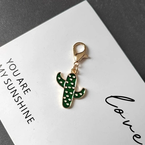 Creative cactus keychain with green enamel finish and gold lobster clasp on gift card