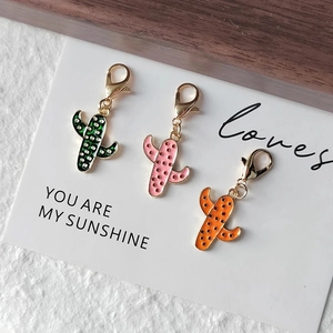 Detailed view of colorful enamel cactus keychains with golden lobster clasps on a card