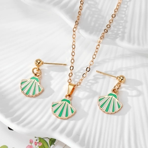 Macro view of shell pendant necklace and ball stud earrings in green enamel and gold