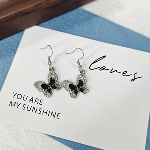 Détail de boucles d'oreilles papillon avec émail noir et cristaux sur crochets argentés