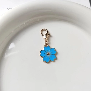 Detailansicht eines blauen Emaille-Kirschblütenanhängers mit Goldrand und Karabiner