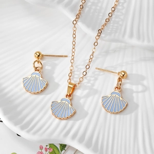 Detail of gold shell jewelry set with blue enamel on a white textured plate
