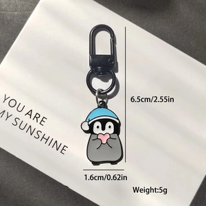Cute penguin alloy keychain with blue Christmas hat and pink heart pendant on white board