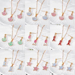 Marine jewelry set with shell and fishtail pendants on elegant white ceramic plate
