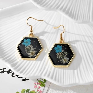 Handmade hexagonal resin earrings with blue dried flowers and gold foil on white shell tray