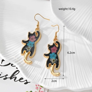 Dettaglio di orecchini a forma di gatto in resina con fiori secchi e ganci d'oro