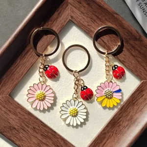 Détail de porte-clés marguerite avec breloques coccinelle sur fond en bois texturé