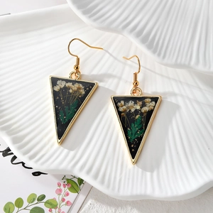 Detail view of triangular resin earrings with real dried flowers and gold foil accents