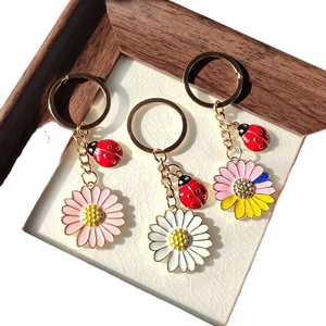 Porte-clés charmant avec marguerite et coccinelle en alliage sur fond de papier blanc