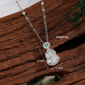 Macro shot of silver gourd pendant with white gemstones and green crystal detail
