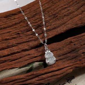 Close-up of hulu pendant necklace with white stones and cubic zirconia on wood