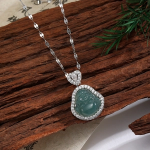 Vue détaillée du pendentif Bouddha avec pierre verte et zircons sur fond de bois ancien