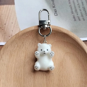 Porte-clés ours polaire floqué blanc avec fermoir en métal argenté sur plateau bois